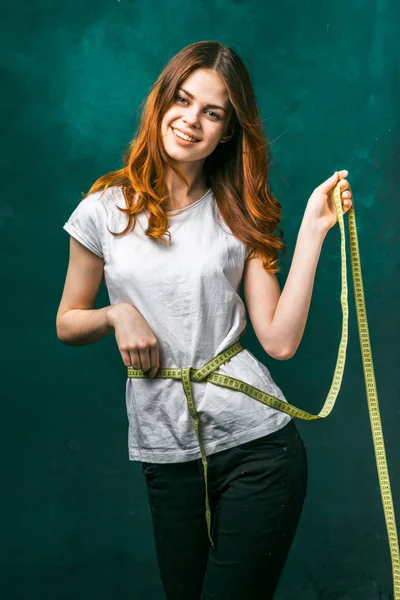 Bonito menina mede sua cintura e olha para a câmera, Perda de peso, dieta, bela figura, em um fundo verde — Fotografia de Stock