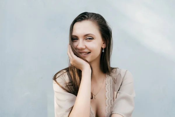 Ridere ragazza coperto il viso con i capelli e guarda la fotocamera, contro il muro bianco — Foto Stock