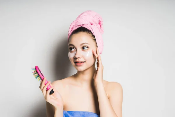 Mysterious girl after the shower holds a colored comb in her hands and looks to the side, isolated — Stock Photo, Image
