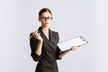 kağıtları ile bir klasör onun elinde tutan ve izole kameraya bakarak güzel kız siyah bir takım elbise ve gözlük,