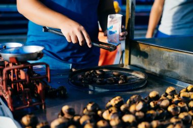 Mavi tulum genç bir adam bir şey kızartma ve bir paket tuz tutan. Adam fry kestane sokakta