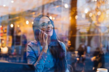 bir kafede çalışıyor, telefonda bir iş bahsediyoruz, gülerek mutlu başarılı kadın serbest meslek