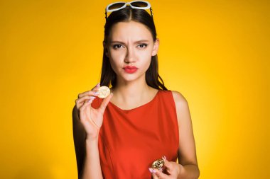 ciddi bir genç kız ellerini, kripto para birimi hakkında düşünüyor bir altın bitcoin tutar