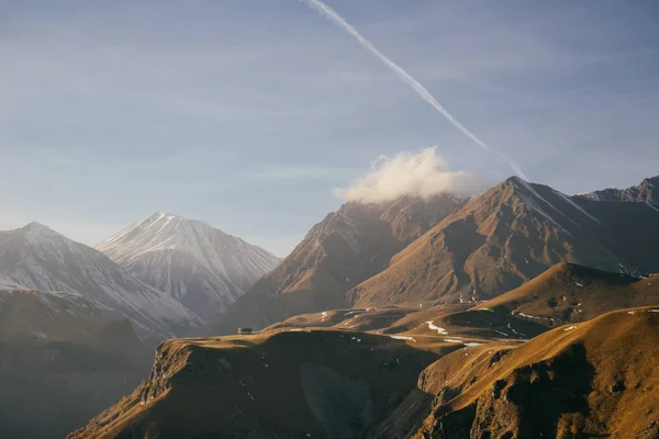 Uma natureza irrealisticamente bela, altas montanhas caucasianas, no céu um traço branco de um avião — Fotografia de Stock
