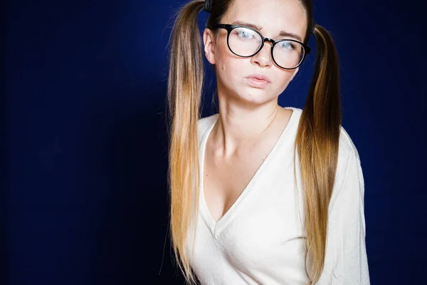 Ernstes Mädchen mit langen Haaren und Brille blickt in die Kamera, isoliert auf blauem Hintergrund — Stockfoto