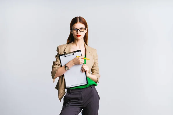 Mujer de negocios seria con gafas está sosteniendo una carpeta con papeles y estrictamente mirando a la cámara, aislado — Foto de Stock