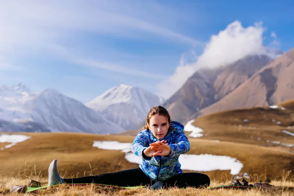 Спортивні молода дівчина мандрівника займається з йоги на тлі кавказьких гір — стокове фото