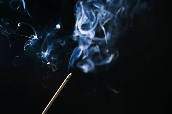 A fekete háttér egy kivilágított parázsló aroma bottal kék füst — Stock Fotó