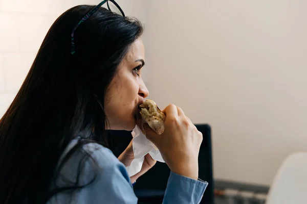 Occupé fille aux cheveux noirs pigiste manger un sandwich dans un café — Photo