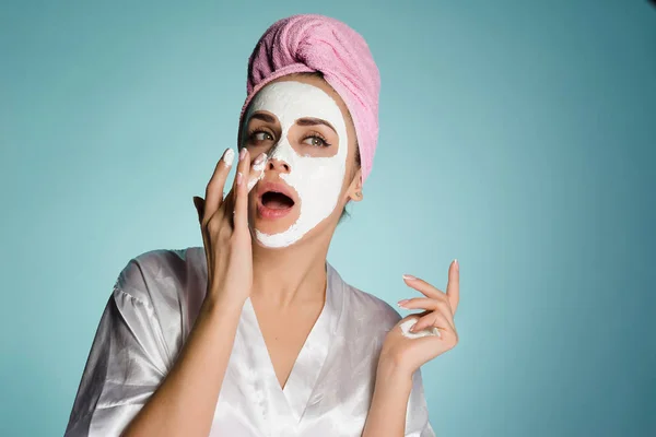 Une jeune fille avec une serviette rose sur la tête prend soin d'elle-même, porte un masque hydratant blanc — Photo