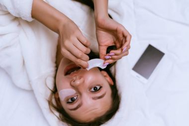 güzel genç kız yatakta, Tutkallar beyaz silikon yamalar gözleri altında yatıyor