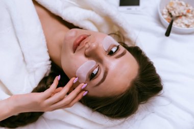 genç bir kız erken uyandım, silikon yamalar, bir tabak yararlı yulaf lapası ile yanındaki gözleri altında yatakta yatıyordu