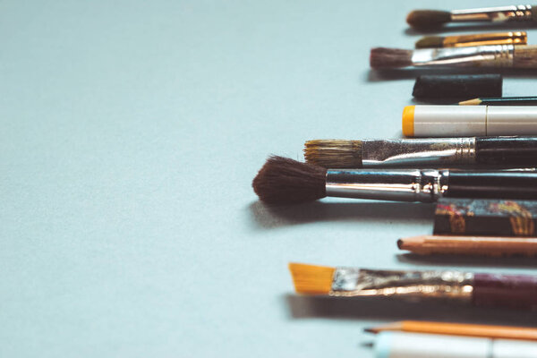 на синем фоне - художественные аксессуары, кисти разных размеров, карандаши
