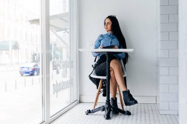 mavi gömlekli zeki genç öğrenci bir tablet üzerinde çalışan bir kafede oturuyor