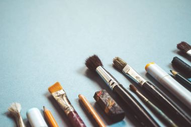 mavi bir arka plan üzerinde birçok Sanat fırçalar farklı boyutlarda, kalemler ve işaretleyiciler vardır