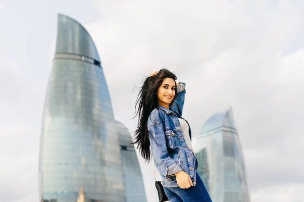 Attractive long-haired girl posing against a background of modern buildings in the city of Baku, in Azerbaijan — Stock Photo, Image