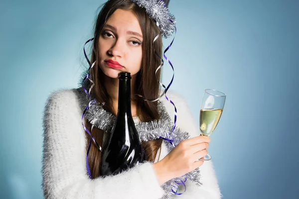 Грустная девушка после празднования Нового года, держит в руках бокал и бутылку шампанского — стоковое фото