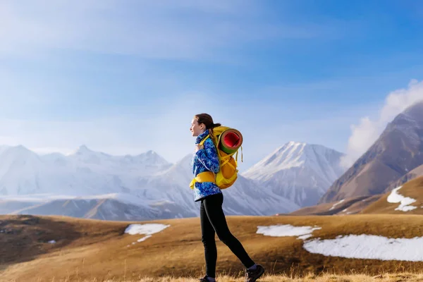 Una joven deportiva en una chaqueta azul viaja a lo largo de la cresta del Cáucaso con una mochila y una tienda de campaña —  Fotos de Stock