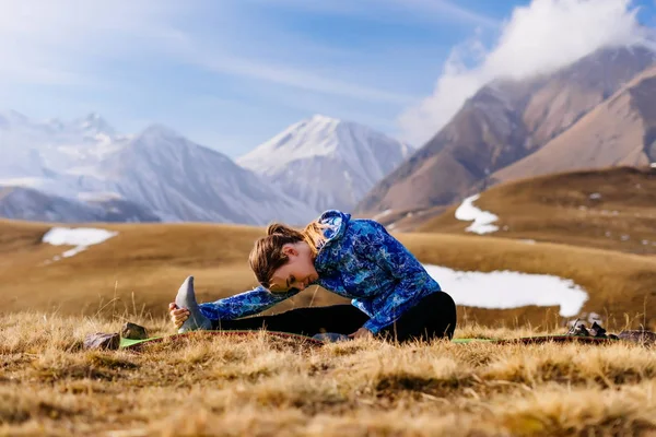 Спортивний дівчинка мандрівник займаються йогою на тлі кавказьких гір — стокове фото