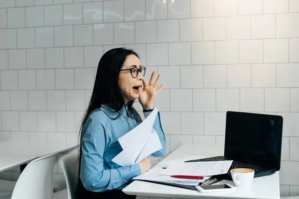 Ontevreden jong meisje met bril werkt op laptop in café — Stockfoto