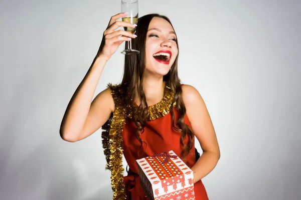 Счастливая молодая девушка, празднующая Новый год, получила подарок, держит бокал шампанского — стоковое фото