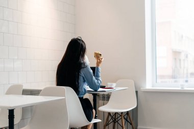 bir sandviçe ve kahveye yemek için bir dizüstü bilgisayar, bir kafede çalışıyor meşgul iş kız