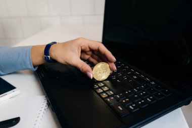 bir dizüstü bilgisayarda çalışan kız yatırımcı altın bitcoin elinde tutan