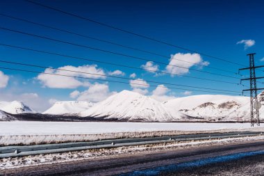 Kuzeyde yüksek karla kaplı dağlar, kış mavi gökyüzü ve sınırsız bir beyaz alan bir görünüm