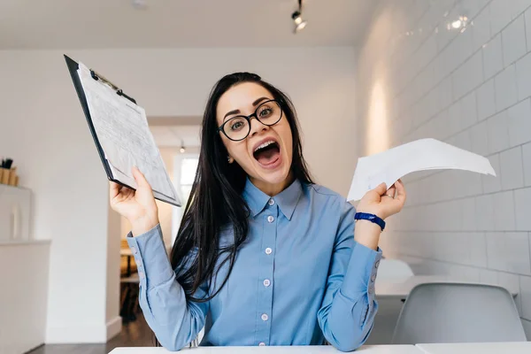 Glückliche Geschäftsfrau mit Brille und blauem Hemd, die in einem Café arbeitet und dann etwas genießt — Stockfoto