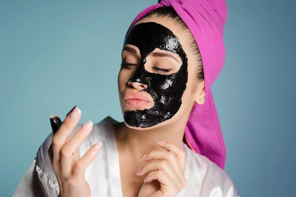 Bela jovem quer ser bonita, em seu rosto uma máscara de limpeza preta — Fotografia de Stock