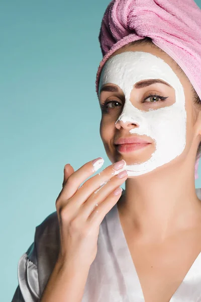 Atractiva joven se pone en la cara una máscara hidratante blanca —  Fotos de Stock