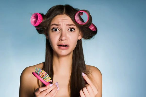 Triste jeune fille n'a pas le temps de faire une coiffure, sur la tête du boucleur de cheveux, tient un peigne dans sa main — Photo