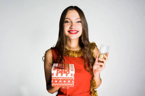 Счастливая улыбающаяся девушка, празднующая Новый год, получила подарок, держа бокал с шампанским — стоковое фото
