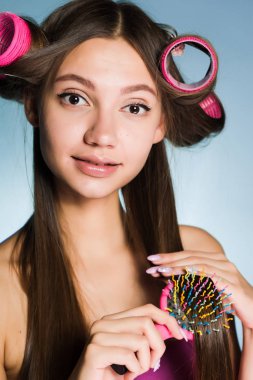 çekici genç kız curlers ve tarak ile şık bir saç modeli yapar