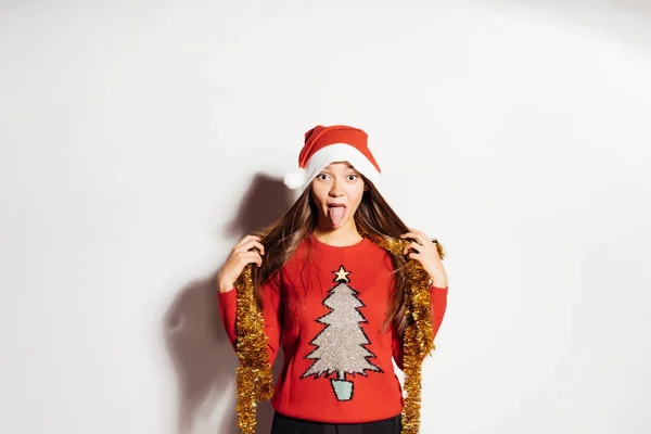 Lustiges junges Mädchen zeigt Zunge in roten Kleidern, die auf Neujahr und Weihnachten warten — Stockfoto