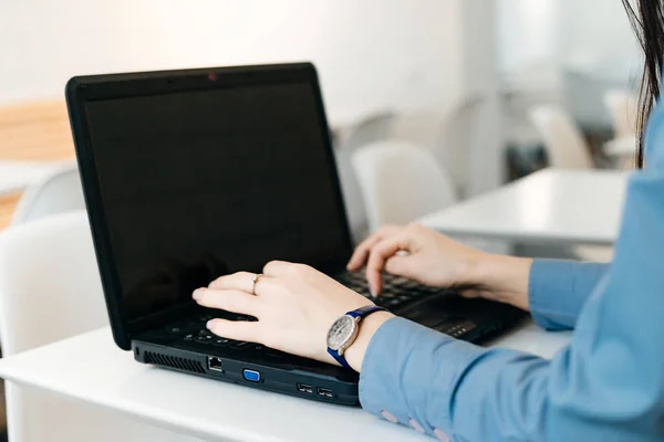 Успешная девушка в синей рубашке, работающая за ноутбуком в кафе — стоковое фото