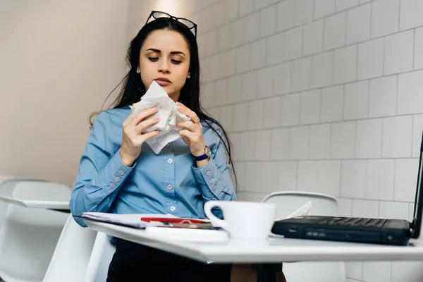 A young busy girl works in a cafe for a laptop, has a sandwich and coffee — Stock Photo, Image
