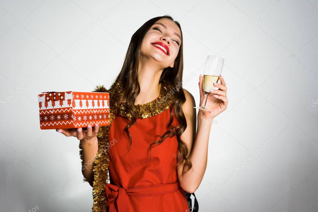 happy young girl celebrates the new year 2018, holds a gift and a glass of champagne