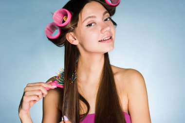 çekici genç kız şık bir saç modeli, onun baş pembe saç curlers yapar, saçları tarak