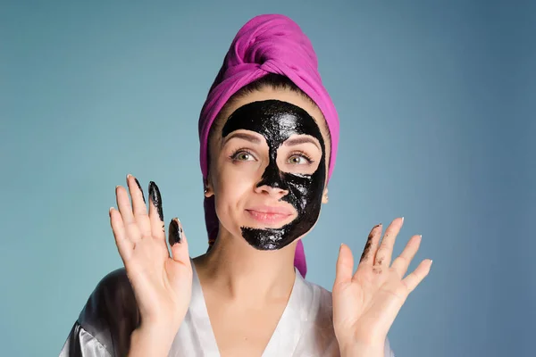 Rolig ung flicka ser ut efter ansiktet, gäller en svart cleansing mask — Stockfoto
