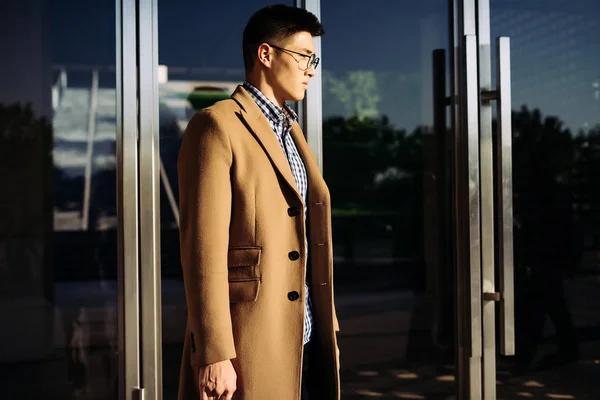 Successful confident young man in a beige coat posing in the sun — Stock Photo, Image