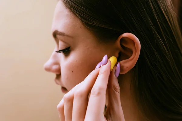 Ein junges Mädchen schläft ein, steckt sich gegen den Lärm gelbe Ohrstöpsel in die Ohren — Stockfoto