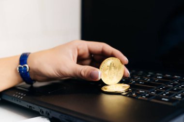bir dizüstü bilgisayarda çalışan kız yatırımcı altın bitcoin elinde tutan