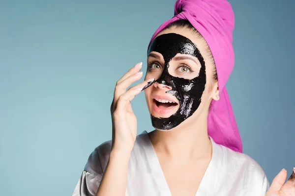 Happy νεαρό κορίτσι θέλει καθαρό δέρμα, ισχύει ένα μαύρο καθαρισμού μάσκα στο πρόσωπό — Φωτογραφία Αρχείου