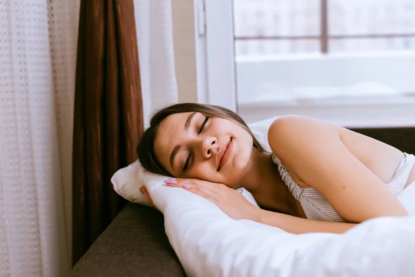 Молодая красивая девушка спит в постели, у нее выходной — стоковое фото