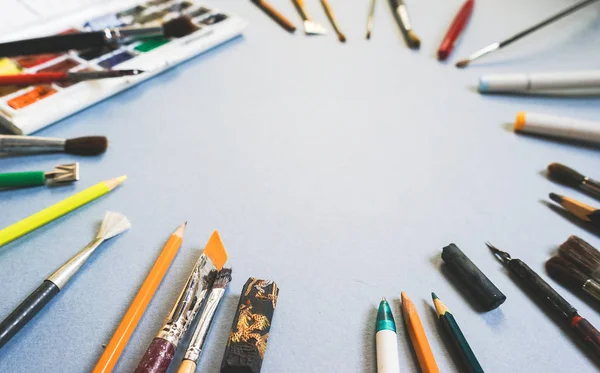 Sur une table grise sont des pinceaux artistiques de différentes tailles, crayons et stylos — Photo