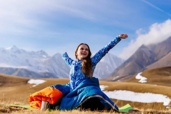 Ein aktives junges Mädchen in blauer Jacke reist den kaukasischen Kamm entlang, genießt saubere Luft, sitzt im Schlafsack — Stockfoto