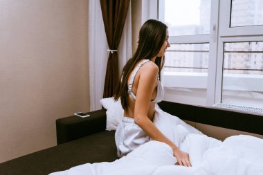 uzun saçlı genç kız erken uyandım, yatakta oturur ve almak istemiyor