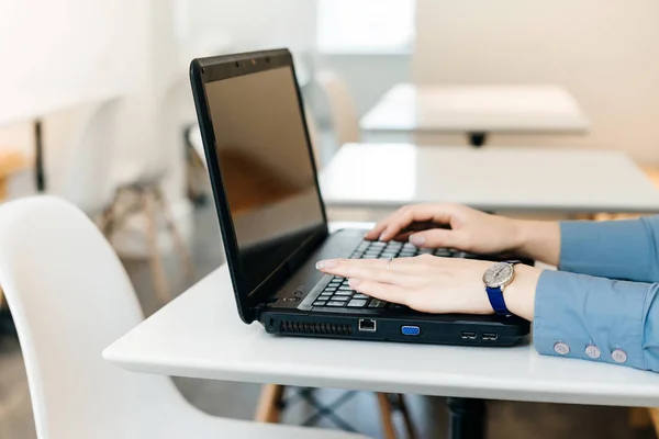 Девушка-фрилансер в синей рубашке усердно работает над ноутбуком в кафе — стоковое фото