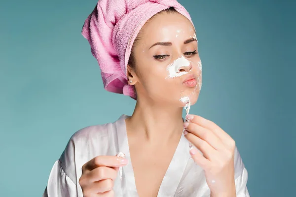 Belle fille enlève un masque blanc utile de son visage, sur sa tête une serviette rose — Photo